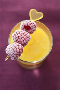 Mango smoothie with frozen raspberry skewer