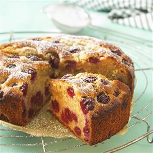 Cherry cake dusted with icing sugar, a piece cut