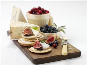 Crackers with fruit and blue cheese on chopping board