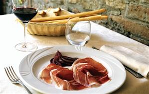 Raw ham with red wine pears, wine and bread basket (Italy)