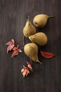 Pears and autumn leaves on wooden background