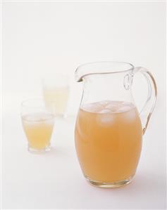 Orange juice with ice cubes in glass jug and glasses