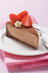 Piece of chocolate cheesecake with strawberries & cocoa powder