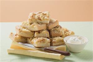 Several pieces of apple crumble cake on plate, cream