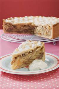 Apple pie with pieces removed, on cake rack, piece on plate