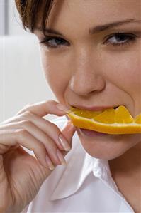 Young woman eating a slice of orange