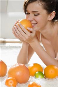 Young woman on a bed with citrus fruits