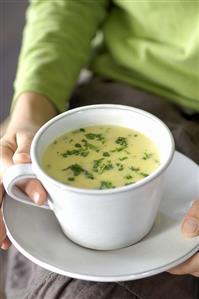 Hands holding soup cup of creamed potato soup