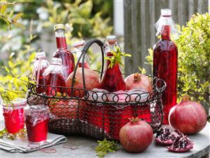 Pomegranate juice, pomegranate jelly & fresh pomegranates on garden table