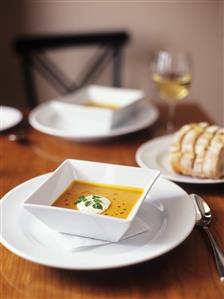 Creamed carrot soup with drops of oil and blob of cream