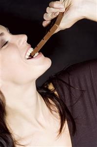 Young woman biting into a chocolate bar