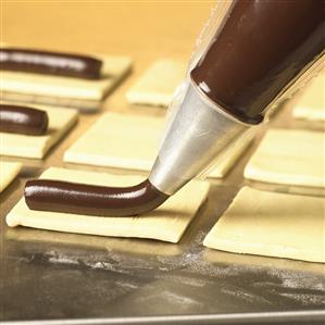 Piping chocolate mixture onto pastry