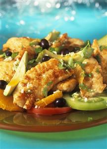 Fried fish with green tomato salad, avocado and oranges