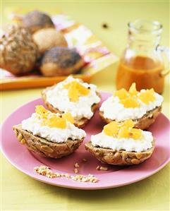 Bread rolls topped with soft cheese and orange