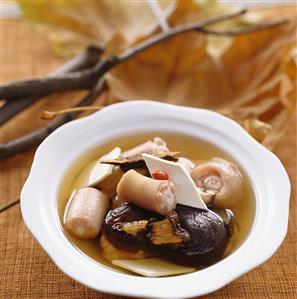 Broth with pieces of pig's tail, yam and mushrooms