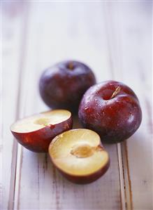 Two whole plums and one halved plum