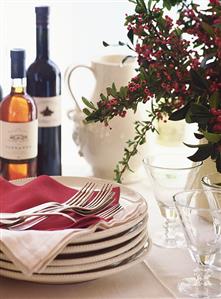 Table with pile of plates, cutlery and wine