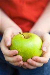 Two child's hands holding an apple