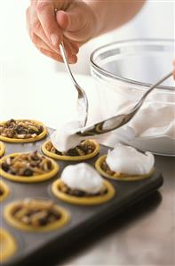 Putting meringue on top of mincemeat tarts