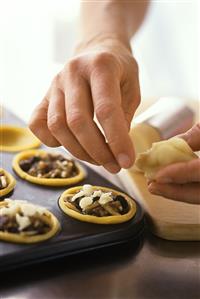 Putting pieces of marzipan on top of mincemeat tarts