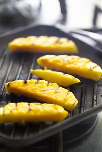 Grilling slices of mango in grill pan