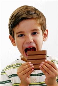 Small boy biting into a bar of chocolate