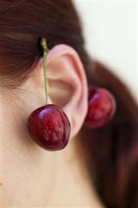 Pair of cherries hanging on a model's ear