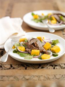 Fried beef steak on mango salad