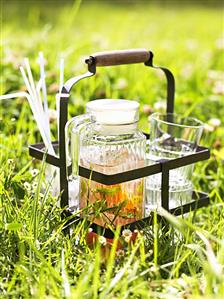 A jug of iced tea and glasses in the open air