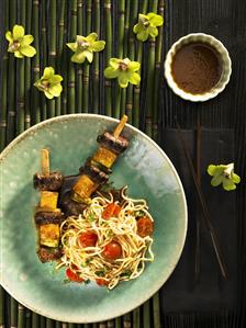 Beef and pineapple skewers with noodles and tomatoes