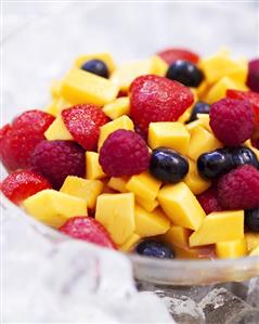 A bowl of mango and mixed berry salad with vodka on ice