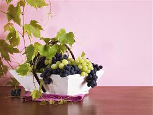 Mixed grapes with vine leaves in a small basket