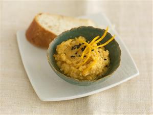 Orange hummus with black cumin and slice of baguette