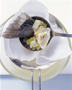 Straining fish stock through a sieve lined with a cloth