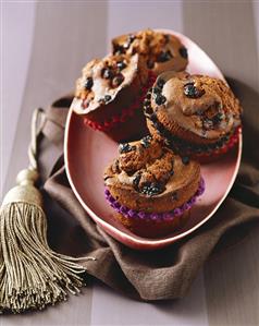 Four chocolate muffins with berries on a platter