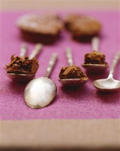 Chocolate cake on silver spoons, cake in background