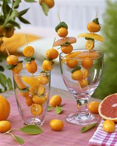 Kumquats, orange & grapefruit segments on skewers in glasses