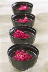 Chicken soup with beetroot sprouts in four bowls