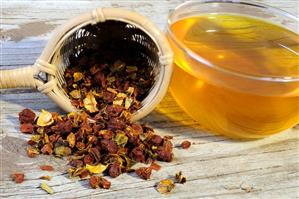 Dried gardenia fruits in a tea strainer with a cup of tea