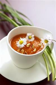 Carrot soup with pine nuts and daisies in a cup