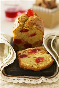 Fruit cake with glacé cherries, partly sliced (UK)