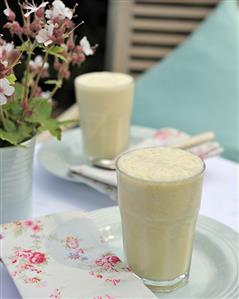 Coconut, banana and mango smoothie in two glasses