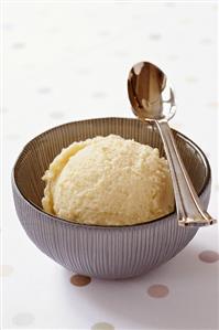 A scoop of banana ice cream in a bowl with spoon