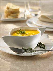 Pumpkin soup with sour cream and thyme in a soup cup