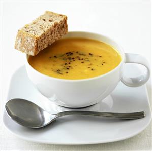 Parsnip soup in a soup cup with a piece of bread