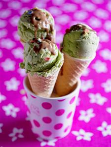 Pistachio ice cream with chocolate sauce in three cones