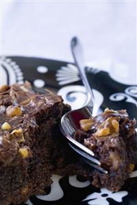 Chocolate nut brownie on a cake plate with fork