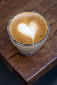 A glass of cappuccino with heart-shaped milk froth