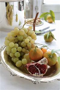 Grapes, mandarin oranges and pomegranate in a silver dish