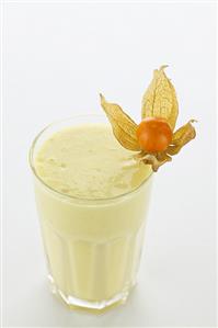 A glass of mango banana shake with a physalis